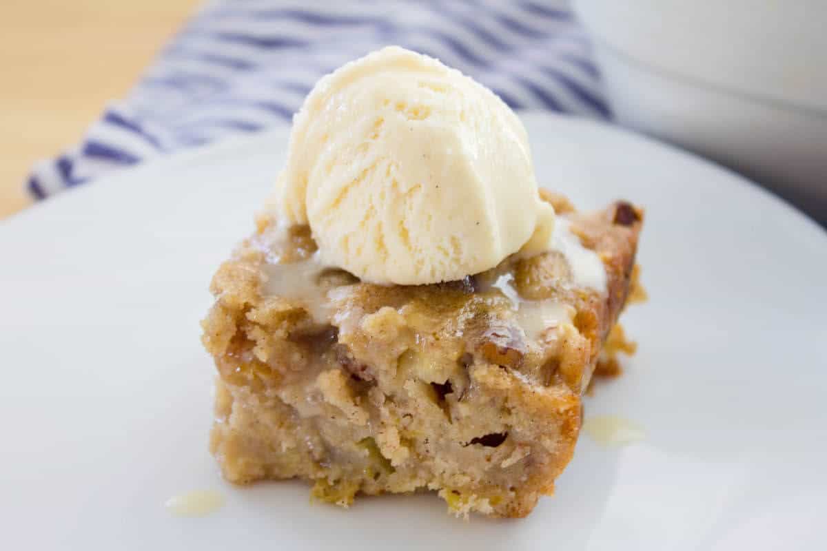 apple spice cake slice with scoop of vanilla ice cream on top