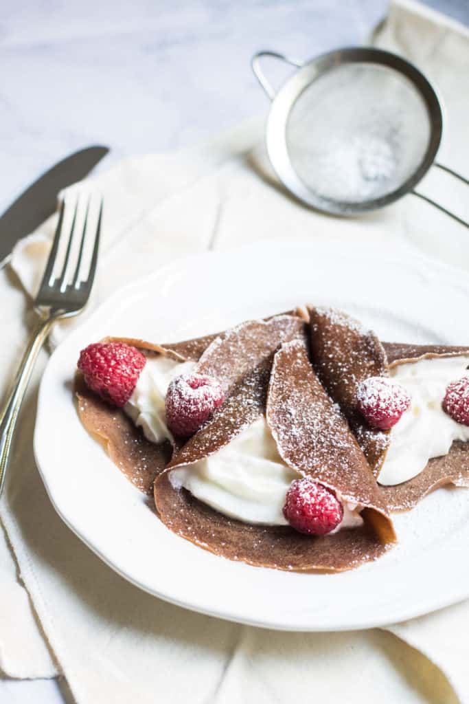 Chocolate Crepes filled with cream and fresh raspberries, then dusted with powdered sugar. So easy and so delicious! Recipe via MonPetitFour.com