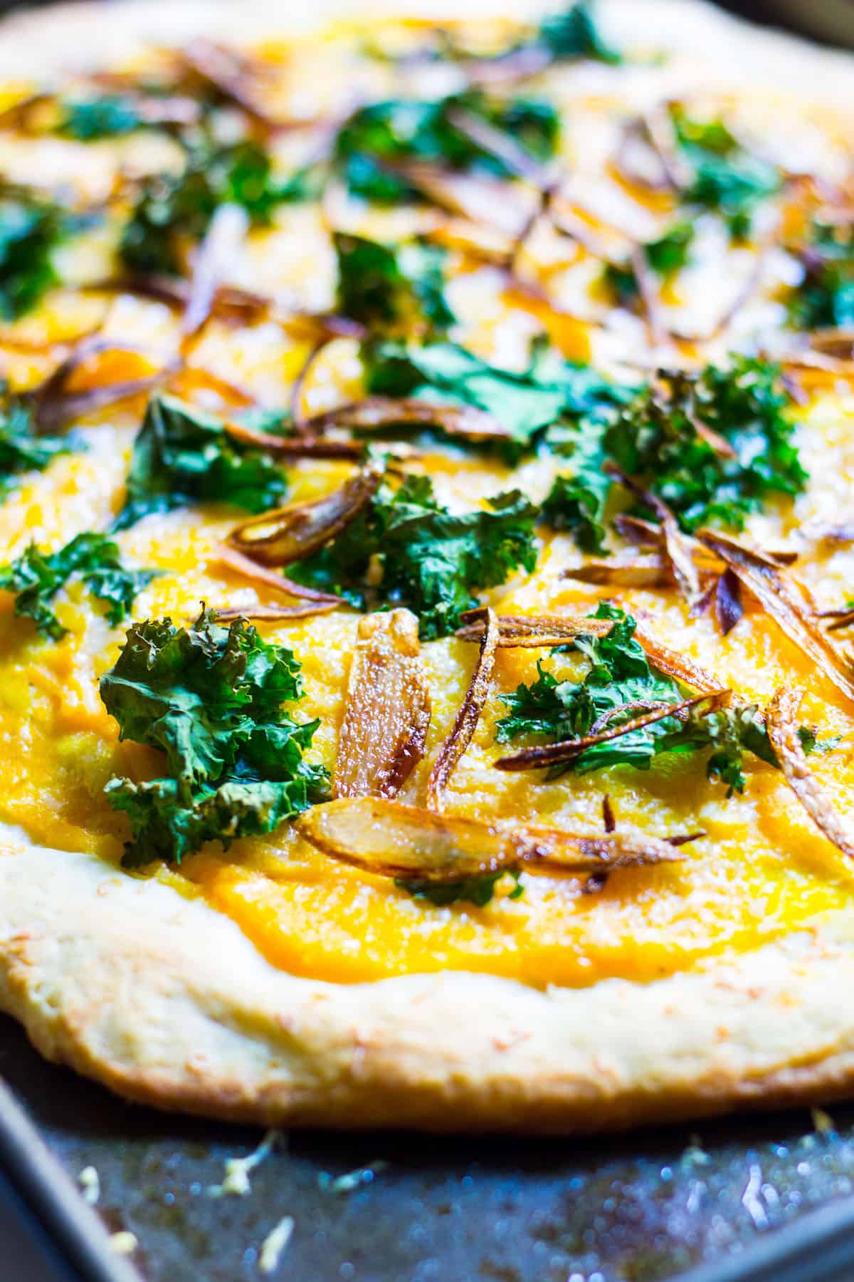 Butternut Squash Pizza: a fall pizza made with butternut squash sauce, gruyere cheese, crispy kale, and crispy shallots all on a homemade pizza crust. Recipe via MonPetitFour.com