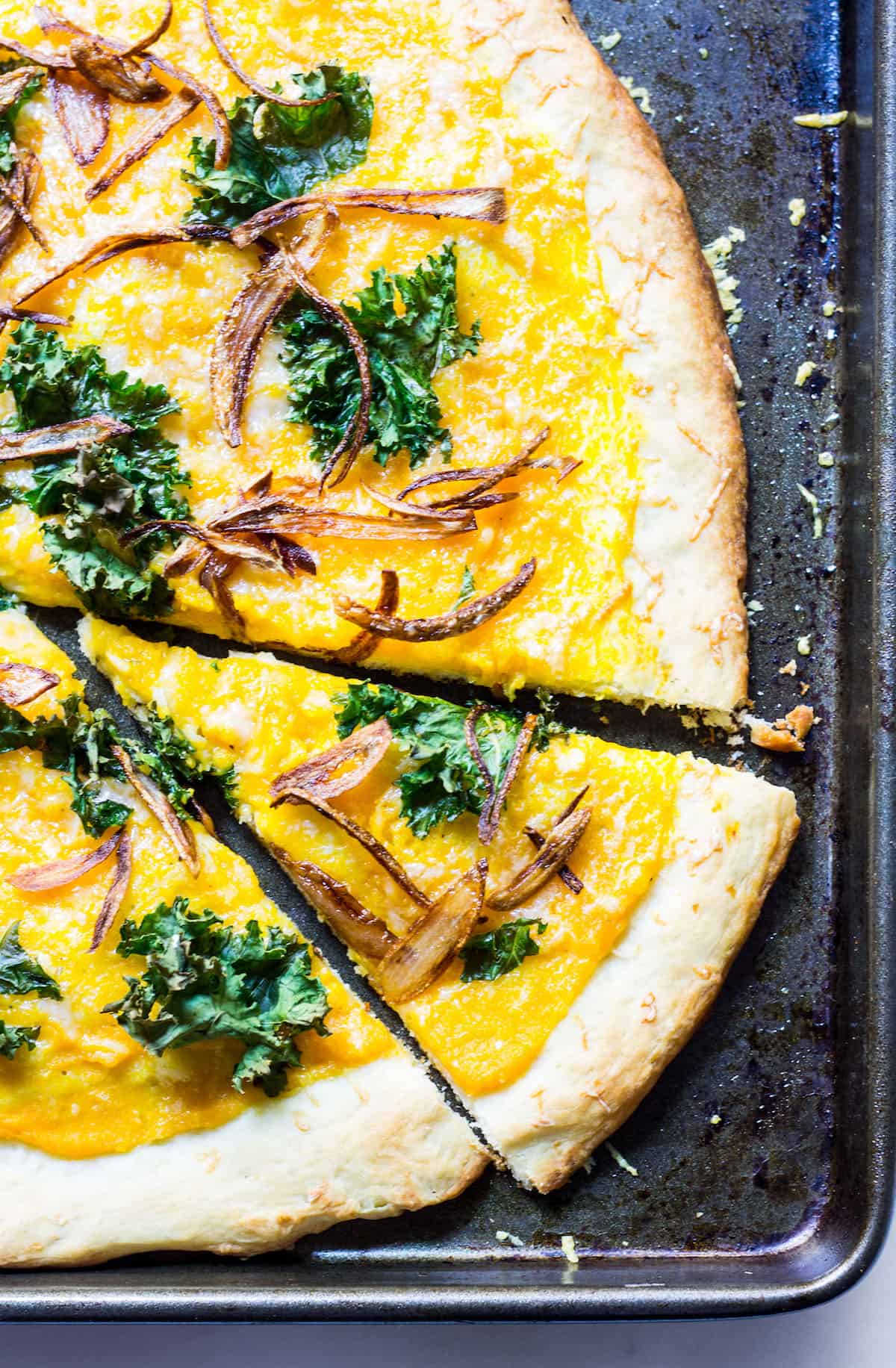 Butternut Squash Pizza: a fall pizza made with butternut squash sauce, gruyere cheese, crispy kale, and crispy shallots all on a homemade pizza crust. Recipe via MonPetitFour.com