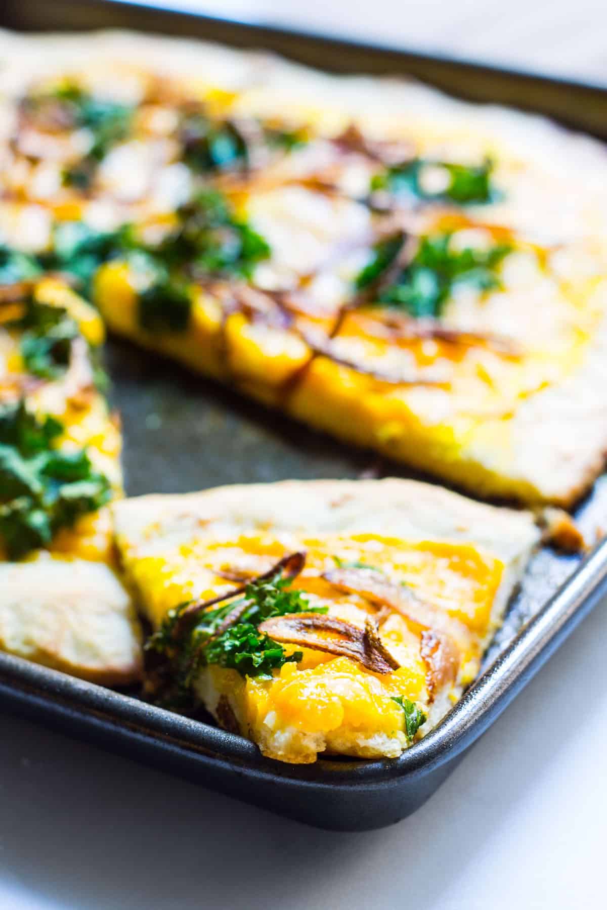 Butternut Squash Pizza: a fall pizza made with butternut squash sauce, gruyere cheese, crispy kale, and crispy shallots all on a homemade pizza crust. Recipe via MonPetitFour.com