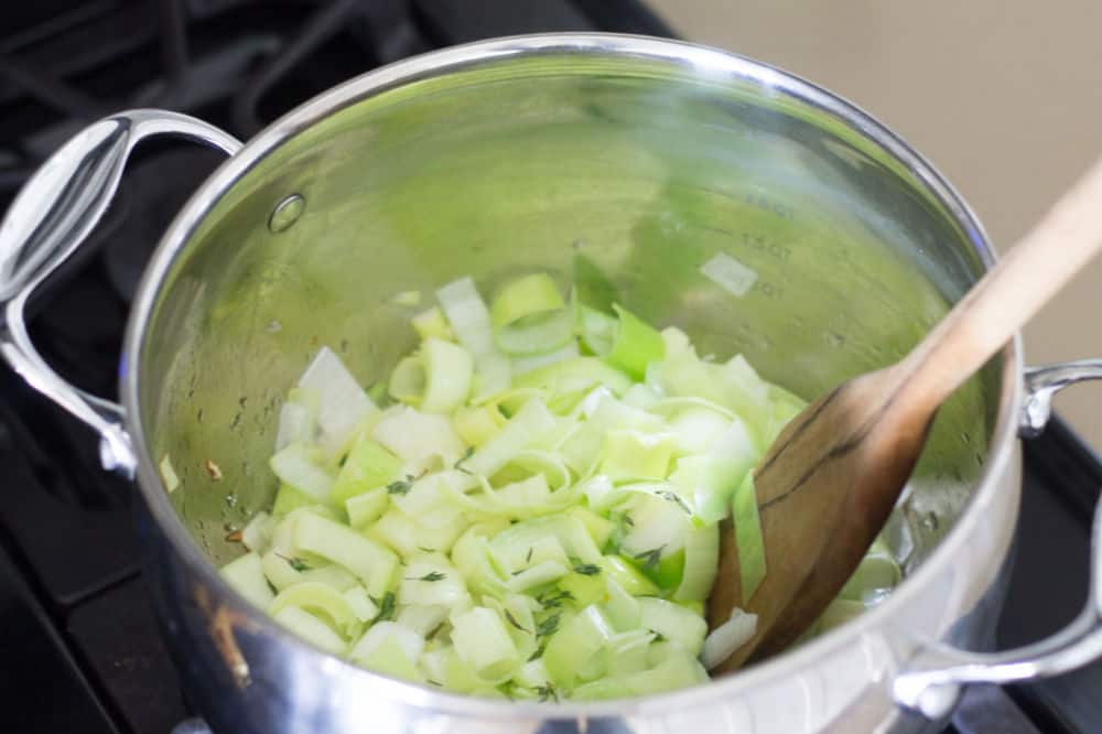 leeks being sautéed in saucepan