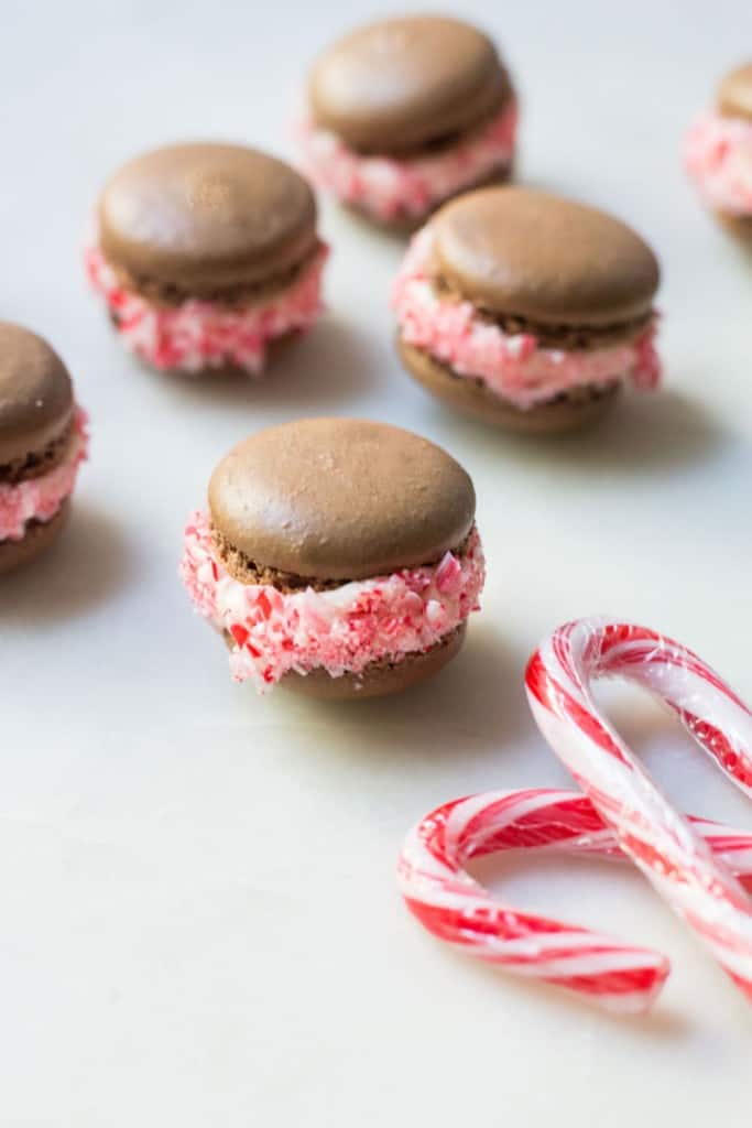 close-up shot of chocolate macarons with peppermint filling and candy canes