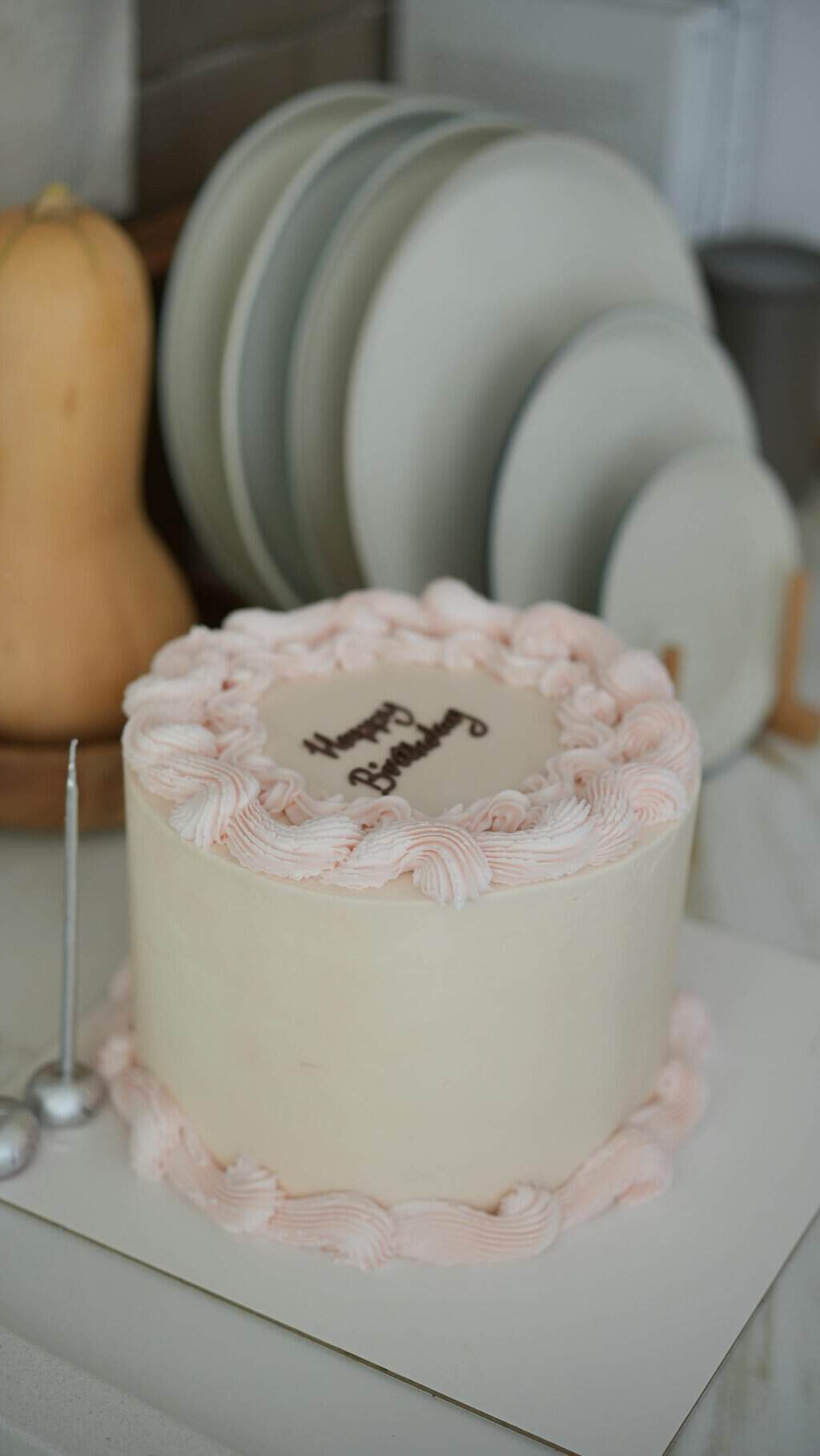 Elegant pastel birthday cake with decorative frosting in a cozy kitchen setting.