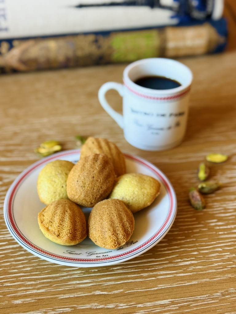 mini pistachio madeleines on a plate next to a cup of coffee