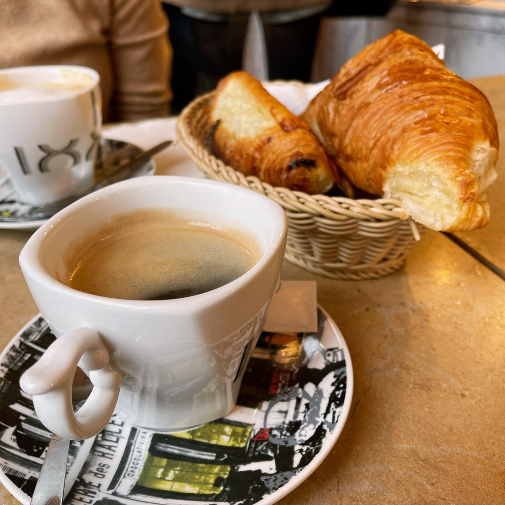 cup of coffee with basket of croissants