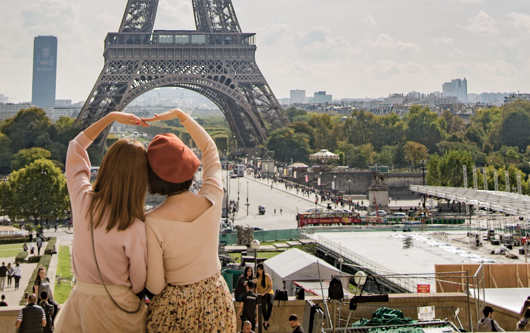 Tourists in Paris admire the iconic Eiffel Tower under a bright sky, capturing a moment of sightseeing and connection.